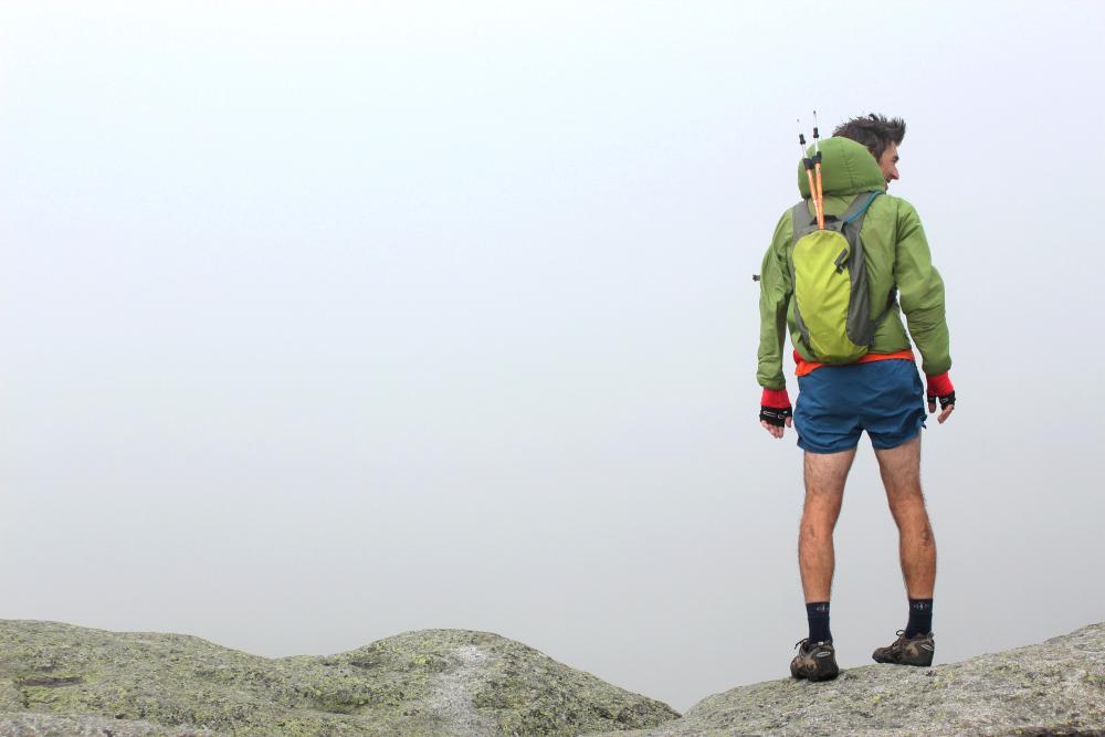 A man stands on top of a rocky point.