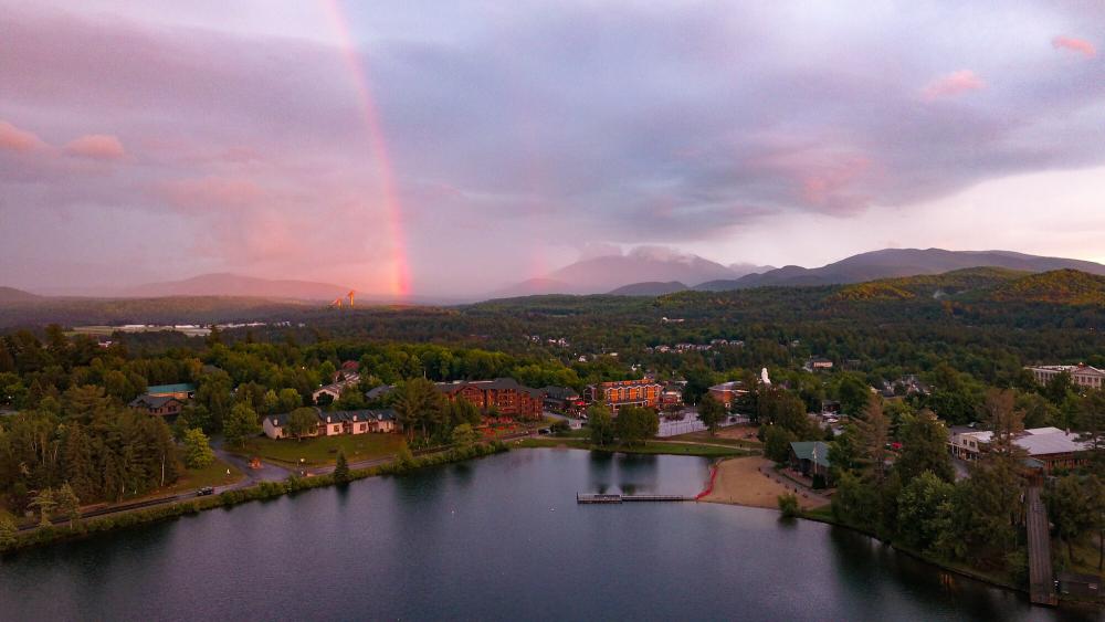 An aerial shot of Lake Placid, hotels, the ski jump and a rainbow.