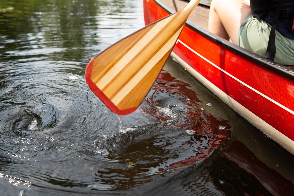 A red canoe and wooden paddle