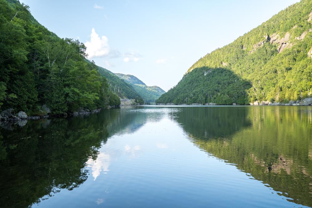 The peaceful waters of an Adirondack lake with dramatic cliffs on each side.