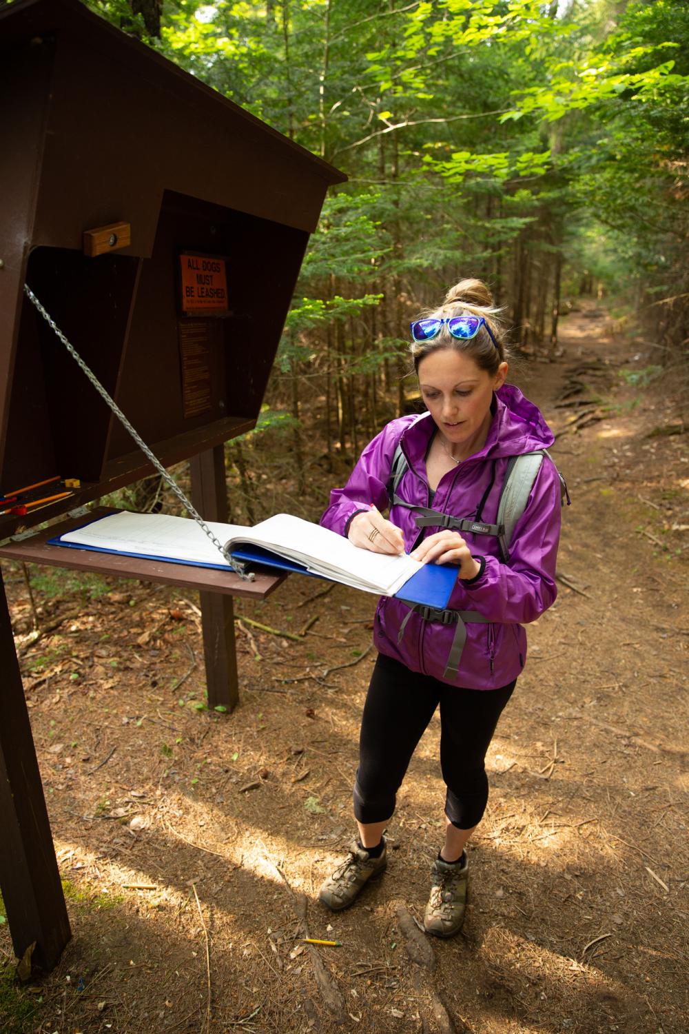 Always remember to register before your hike A hiker registers at trailhead