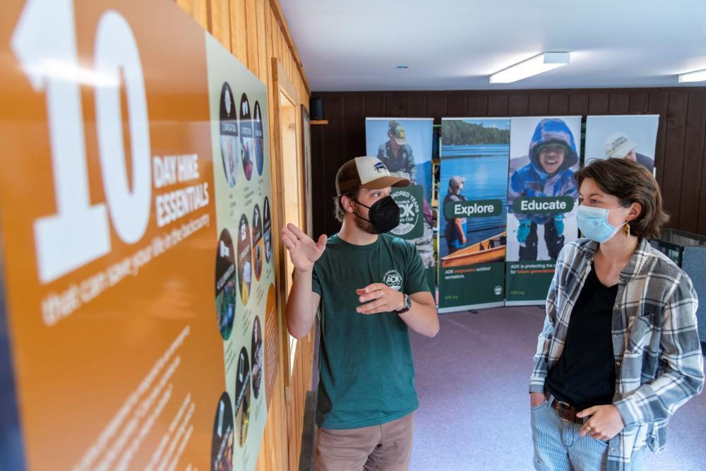 A guide helps a visitor read an information poster.