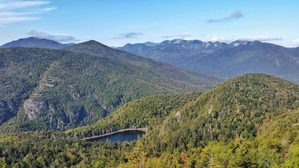 Green leaves, just starting to change to fall colors, make up most of this mountain view.