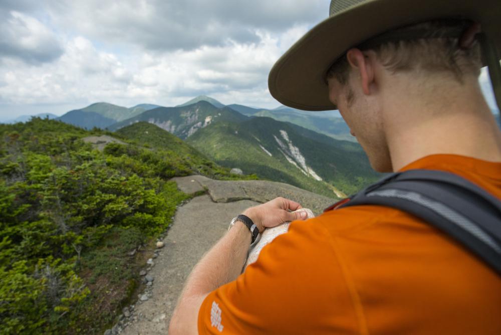 A hiker checks a map on the summit of a mountain