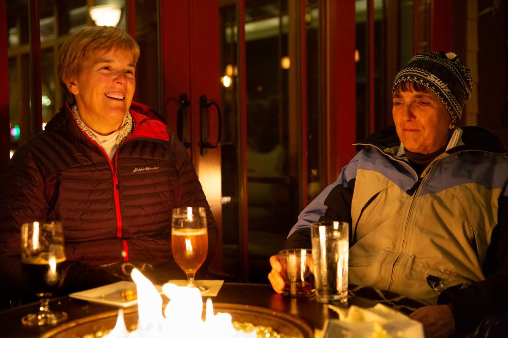 two women eating food by a campfire