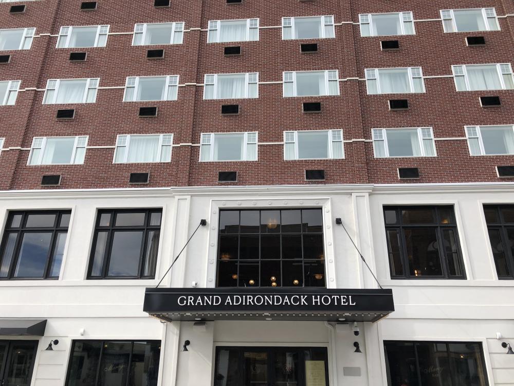 A street view of Grand Adirondack from the street with windows and front entrance sign.