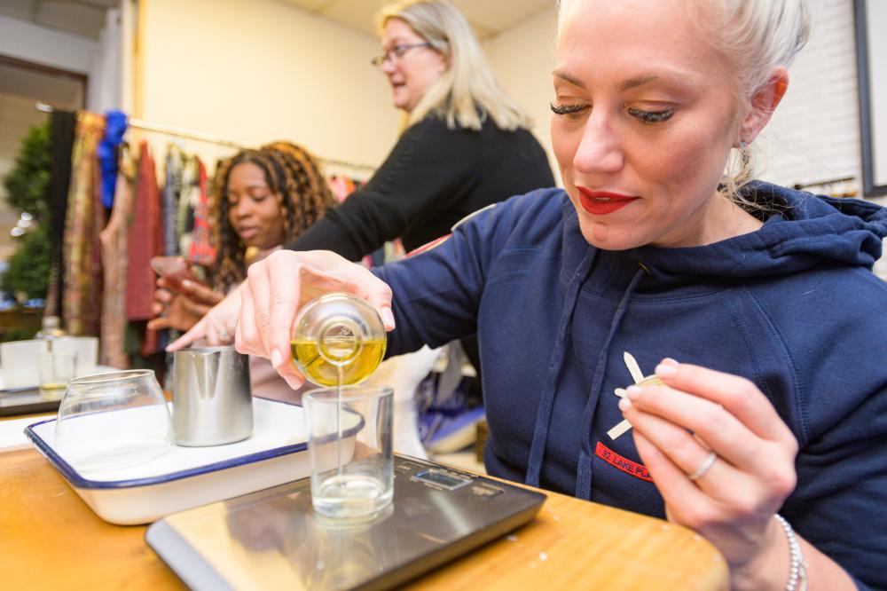 A woman pours oil into a glass jar in a shop.