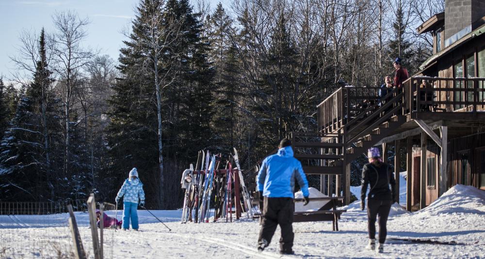 People outside the lodge at Cascade with skis on a rack