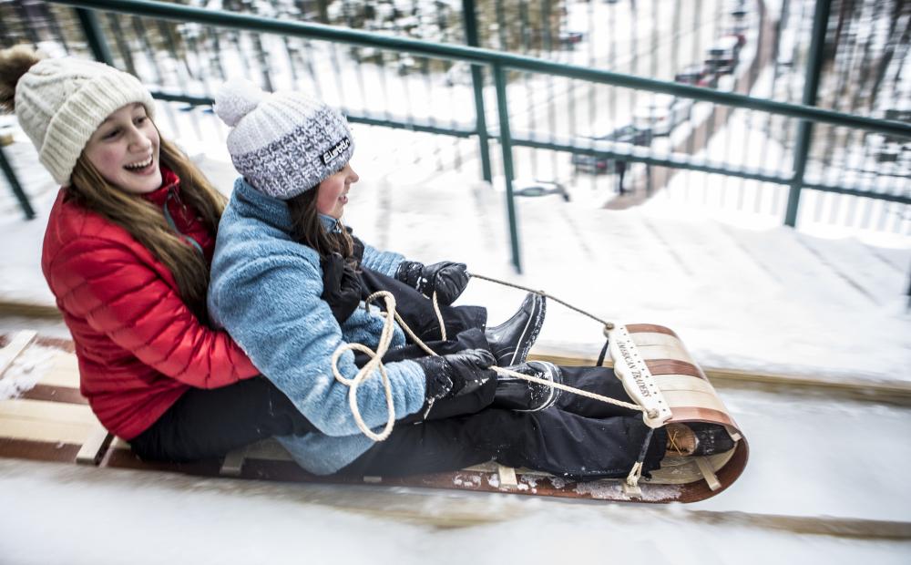 two girls on a toboggan slide down a 30 foot chute