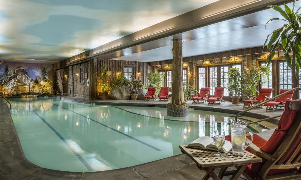 A view of the indoor pool at the Mirror Lake Inn Resort and Spa, with lounge chairs lining the edges of the pool walkway