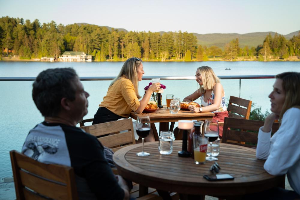 People dine outdoors on a deck overlooking Mirror Lake.