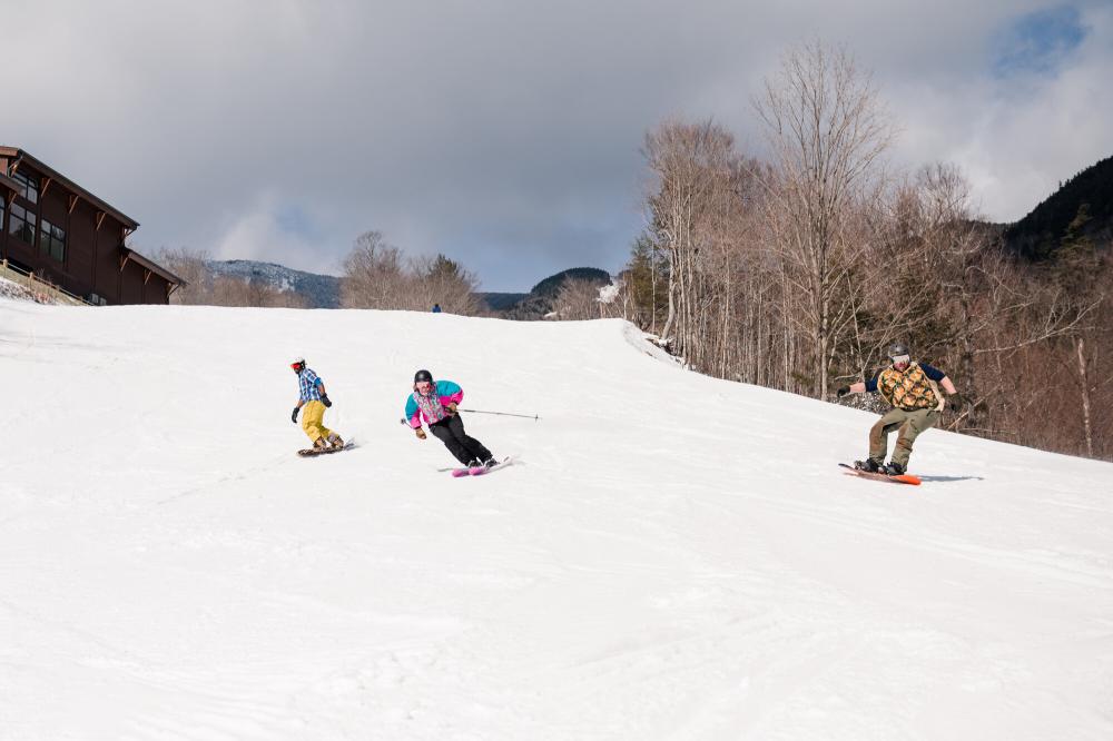 Skiers and boarders carve their way down a snowy slope.
