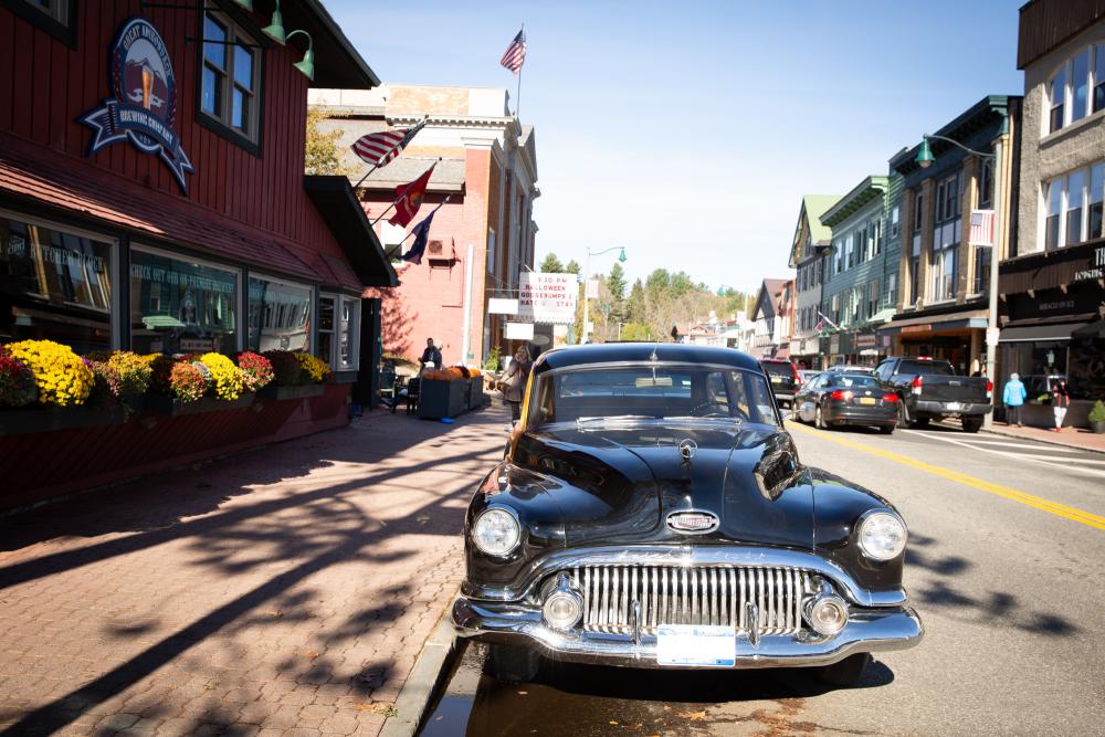 A vintage black car is parked on a small town Main Street.