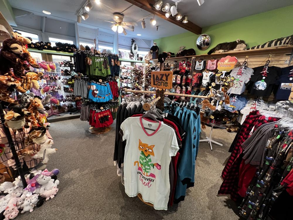 A brightly colored shop filled with racks of clothing and shelves of stuffed animals.
