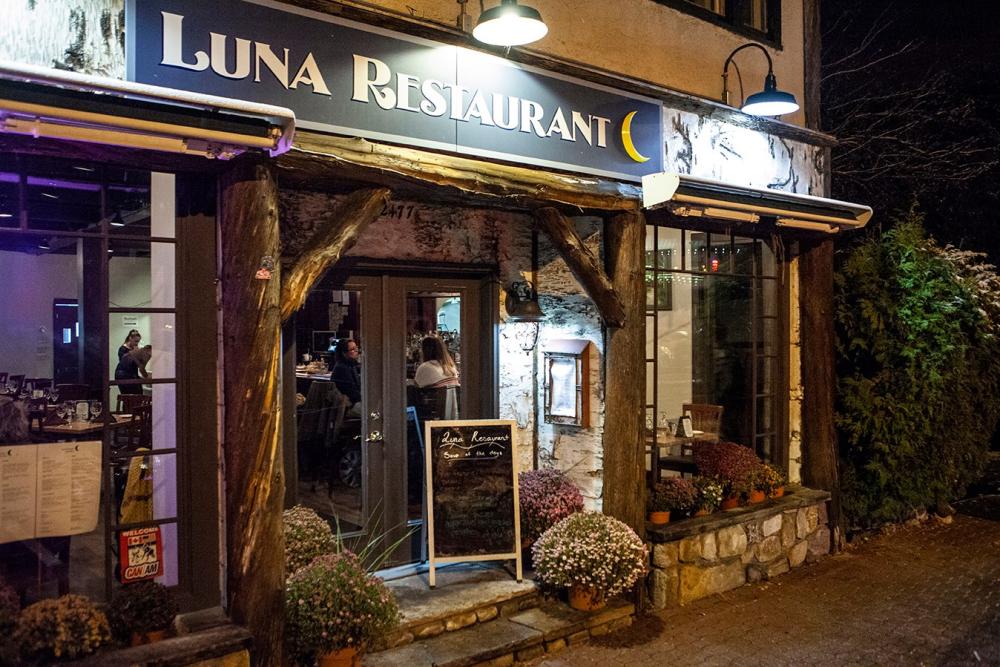 The exterior of a wood and birch bark trimmed restaurant. The sign reads Luna Restaurant.
