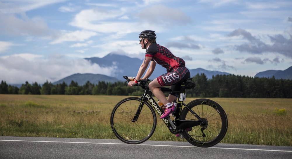 A cyclist rides the Ironman course amidst high peaks scenery in the Lake Placid Ironman competition