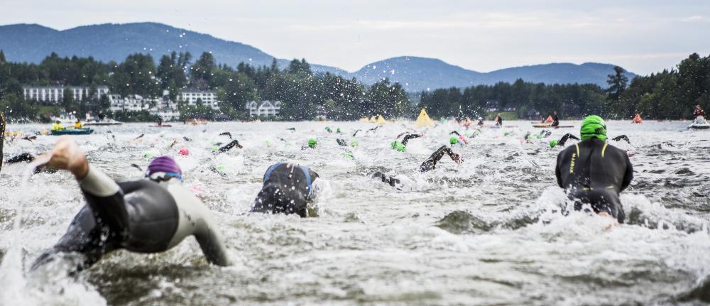 A group of swimmers splashes in the water of Mirror Lake on the morning of the Ironman Race in Lake Placid