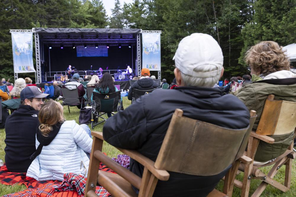 People sit in lawn chairs in the grass at Open Sky Music Festival