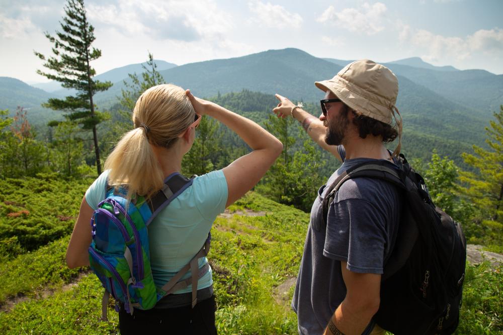 A man shows a woman the view of a mountain in the distance.