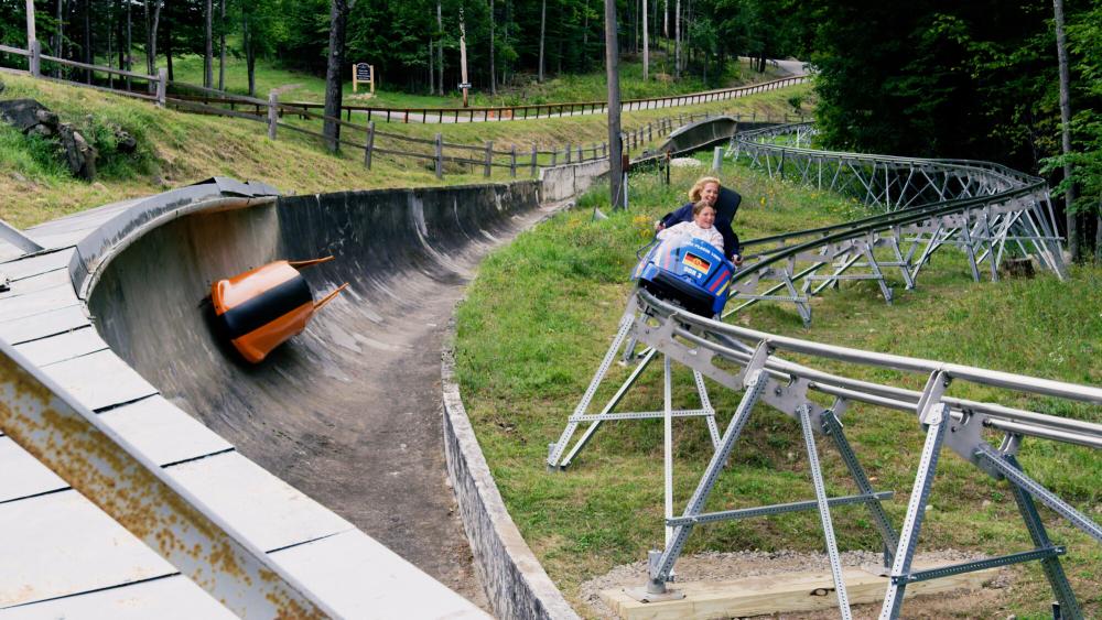A woman rides a curve on a mountain coaster rail.