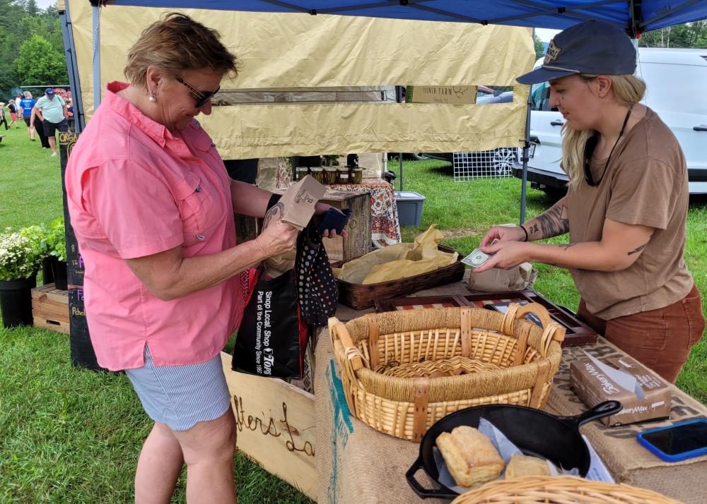 A woman buys a loaf of bread from Courtney Marvin at The Drifters Loaf, located at the Keene Farmers Market