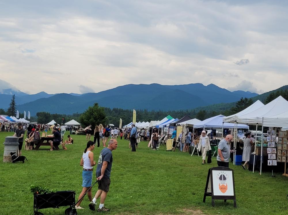 The Keene farmers market hosts many vendors, hundreds of people with their dogs, and offers a scenic view at the side of March field. The Adirondack Mountains are in the background.