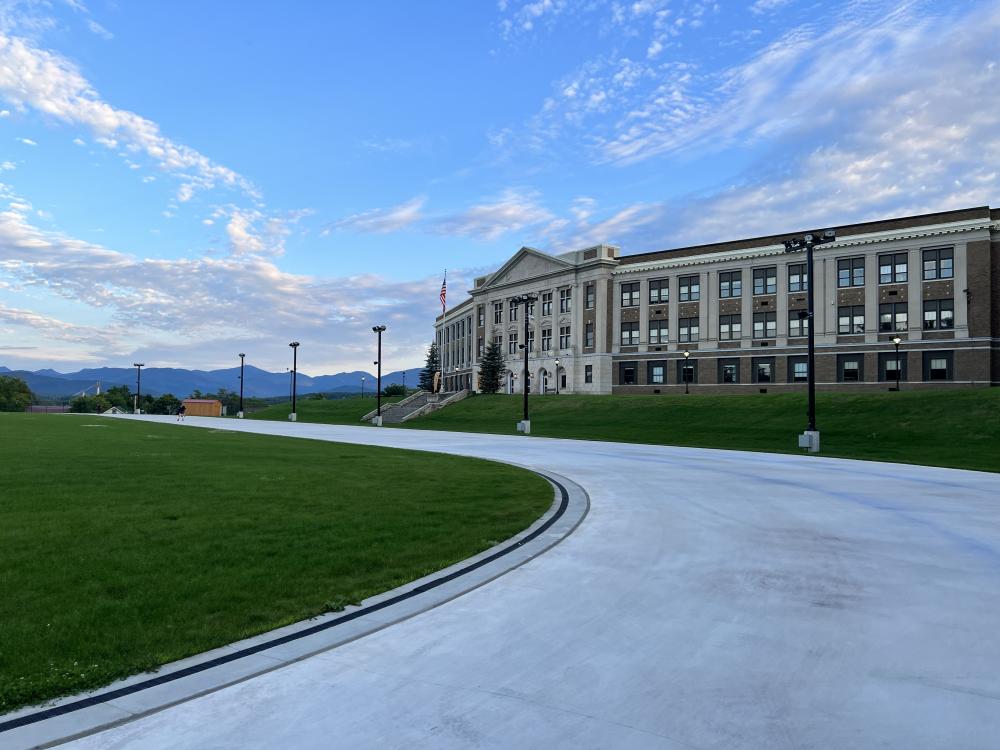 The Oval surface as seen from the first turn (photo/Christie Sausa). A stone high school overlooks a smooth skating track on a summer day.