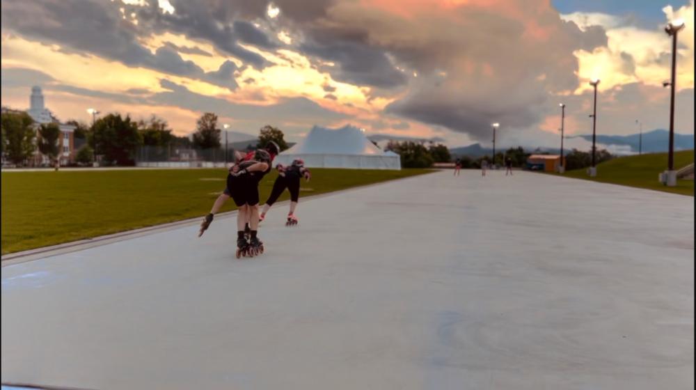 Two inline skaters race towards a pink sunset.
