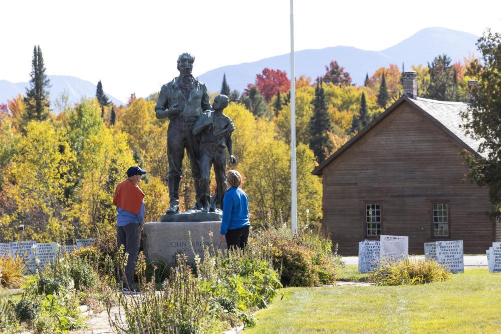 Two people view a memorial statue at John Brown Farm in Lake Placid