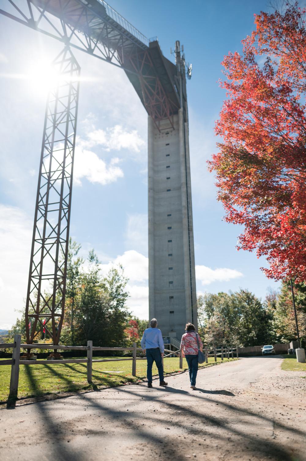 A photo of one of the ski jumps at the Olympic Jumping Complex in Lake Placid, with fall foliage in the distance