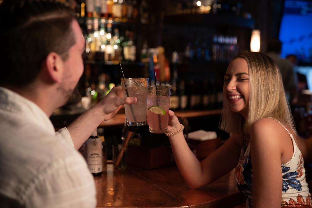 A man and woman share drinks at a bar.