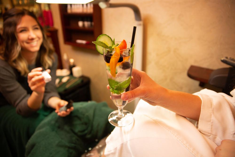 A woman's hand holds a mineral water adorned with a fresh citrus wedge in a Lake Placid spa