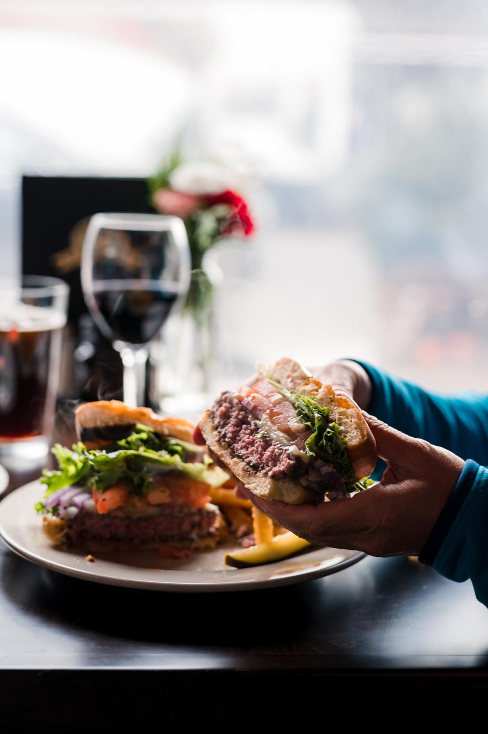 A woman holds a burger to eat.