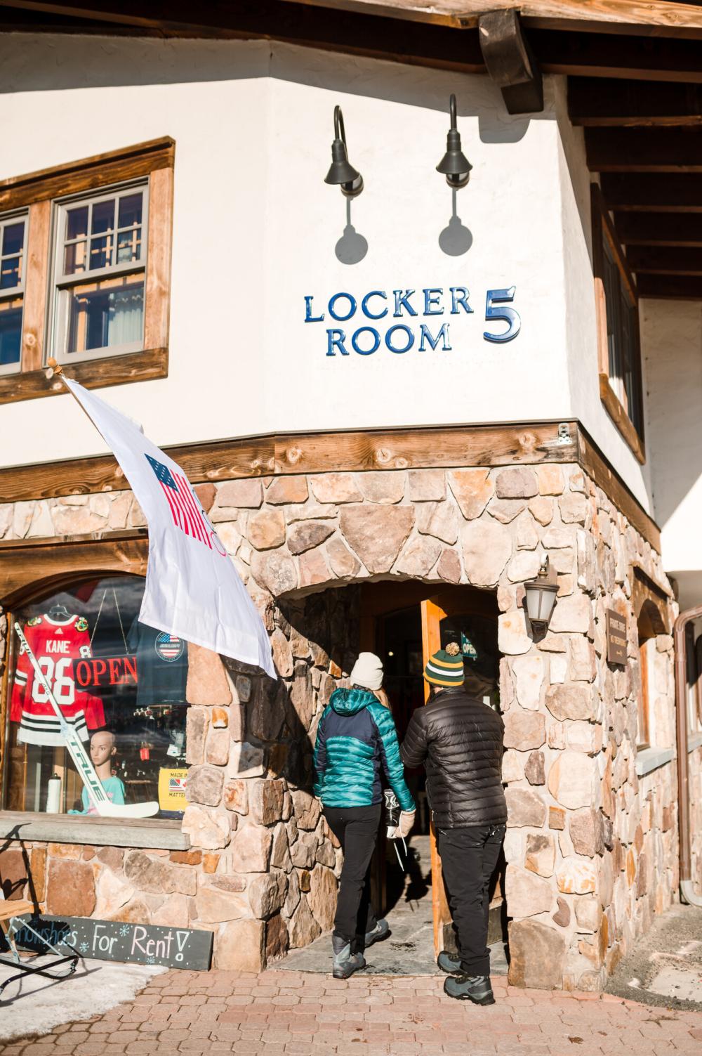 Two people walk into a store front in winter.