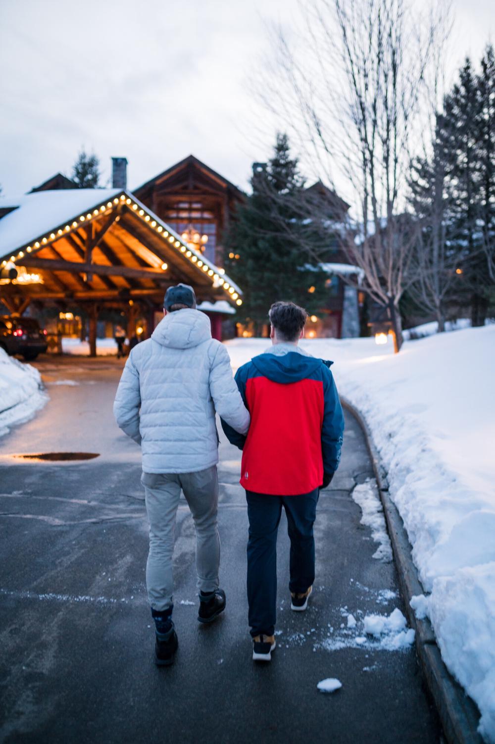 Two men walk up to a winter lodge.