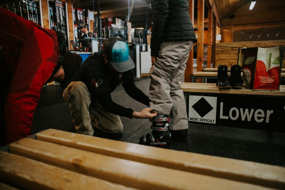 A ski tech helps someone fit a boot.