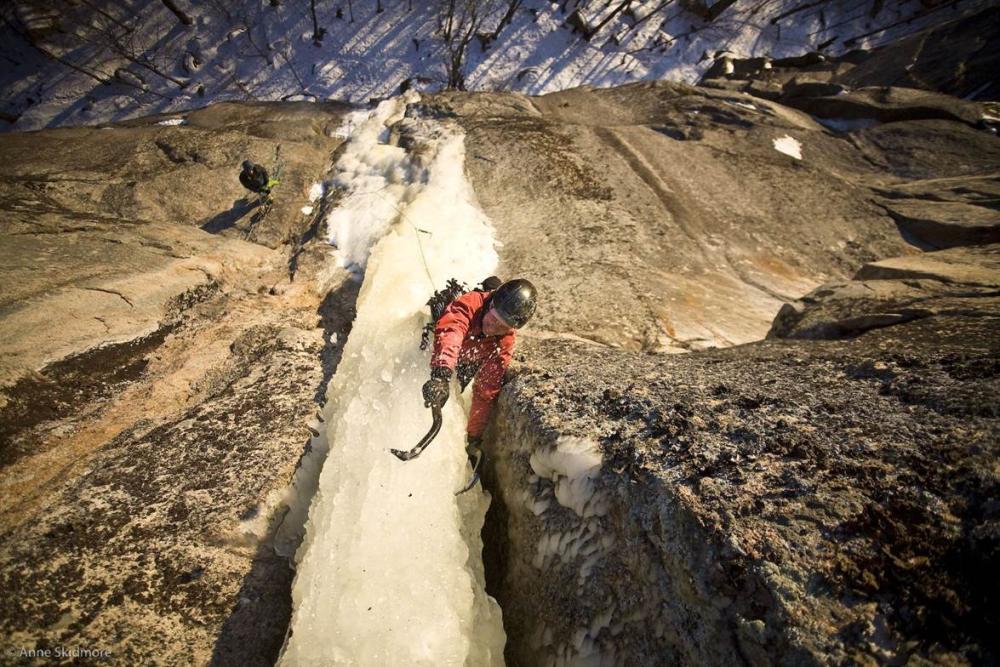 A person ice climbing a narrow dagger of ice