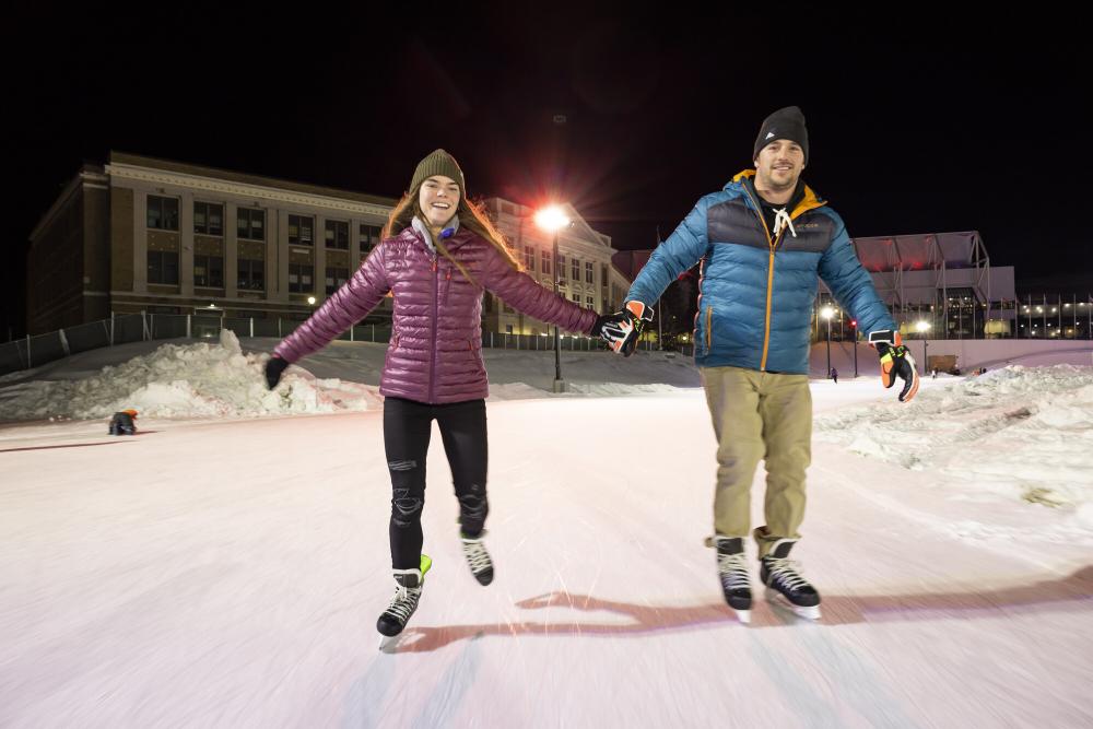 Two people skate during the evening hours after dark at the Olympic Oval