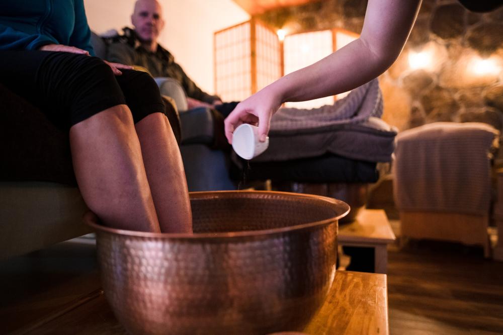 A person soaks their feet in a large copper kettle at The Adirondack Foot Sanctuary