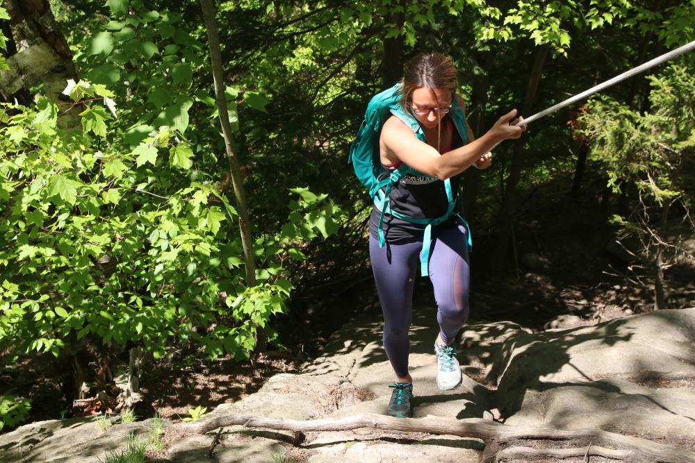 A woman uses a trail rope to pull herself up.