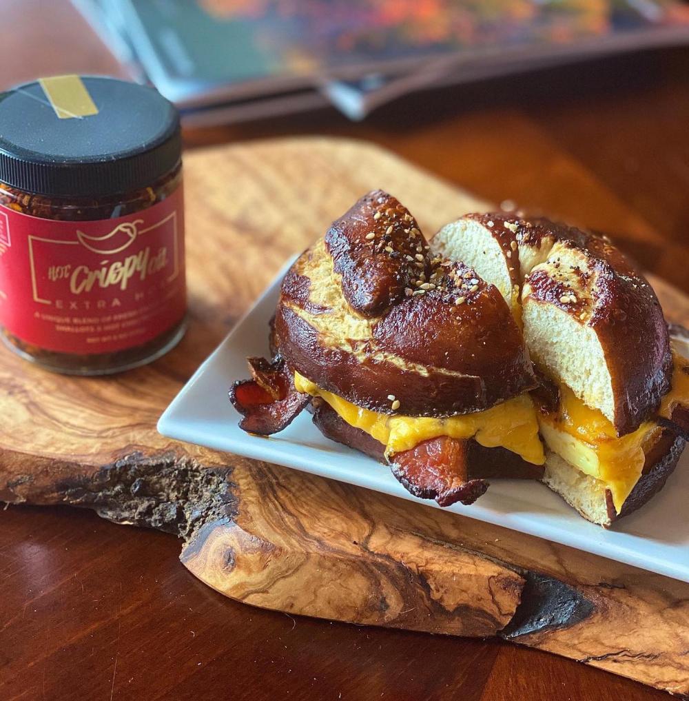 A bacon egg and cheese sandwich on a pretzel bun on a plate.
