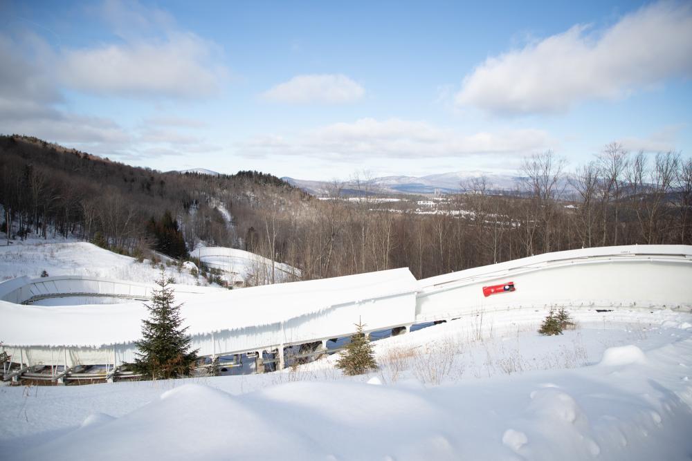 Bobsled at Mt Van Hoevenberg Red bobsled slides down track with mountains in background