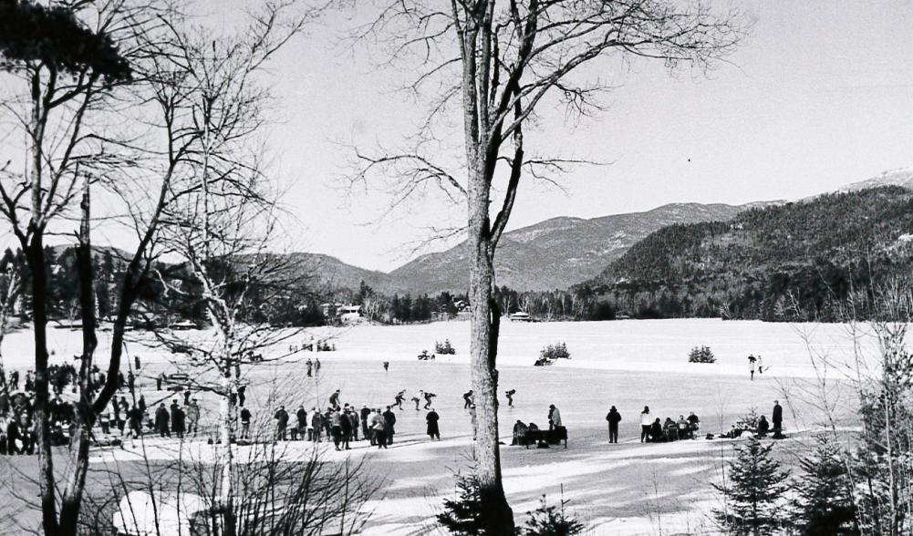 A vintage black and white image of people skating on a frozen lake.