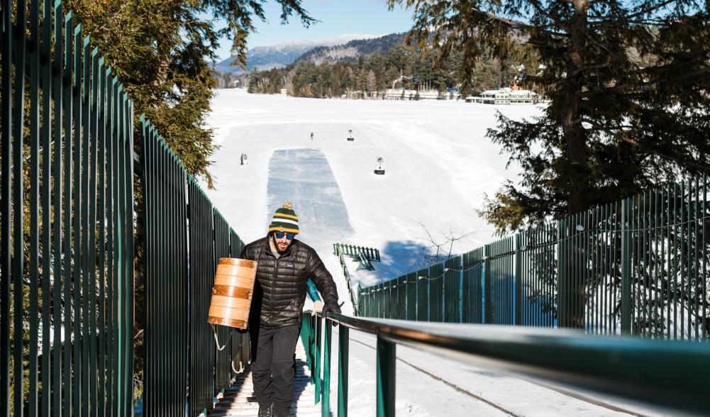 A man hauls a toboggan to the top of the Lake Placid toboggan chute.