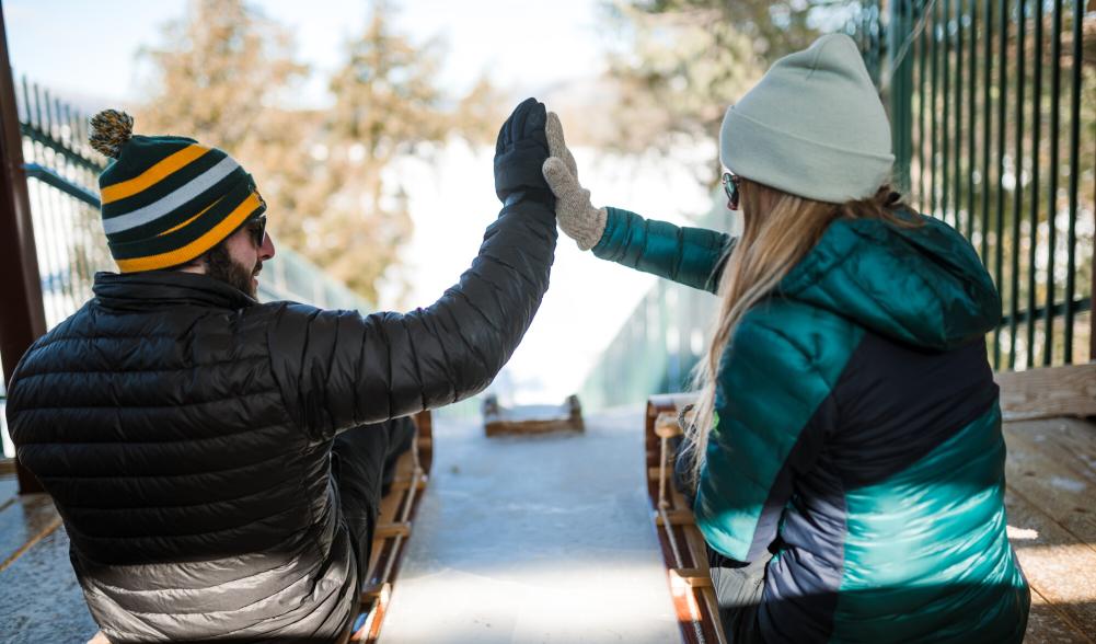 A couple sits on toboggans at the top of the Lake Placid toboggan chute