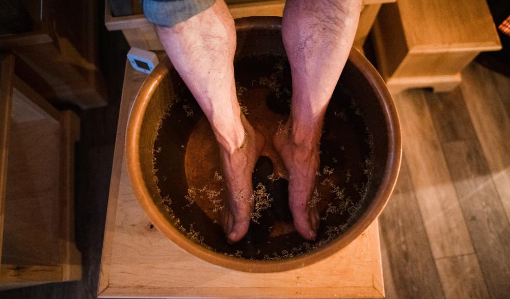 A man's feat are soaking in a steel tub.