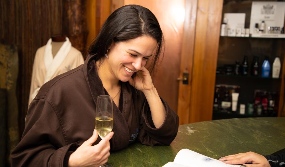 A women looks through the spa menu as she enjoys a glass of wine
