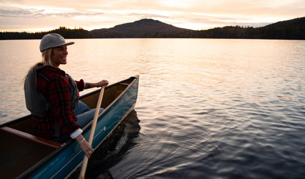 a woman paddles at dusk on the lake.