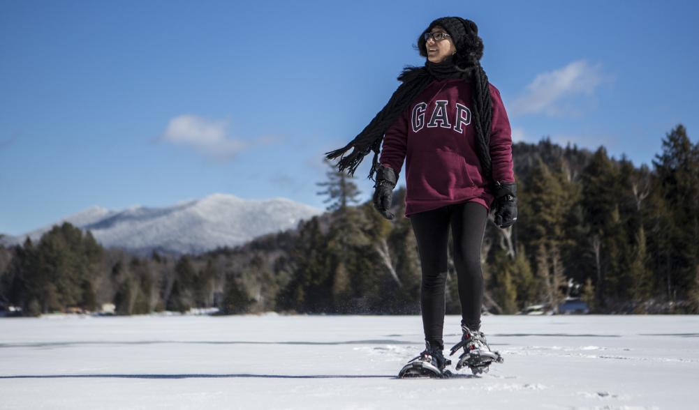 A girl snowshoes across Mirror Lake on a warmer day