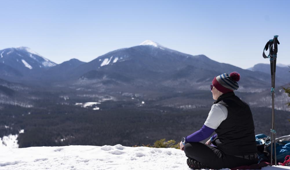 A winter hiker soaks up the view from the top of Mt. Van Hoevenberg in the winter.